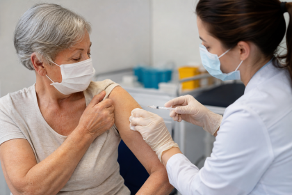 Pessoa idosa recebe vacina contra doenças pneumocócicas em unidade de saúde