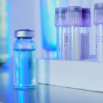 Frascos e tubos de ensaio com líquido azul em um laboratório sob luz fluorescente
